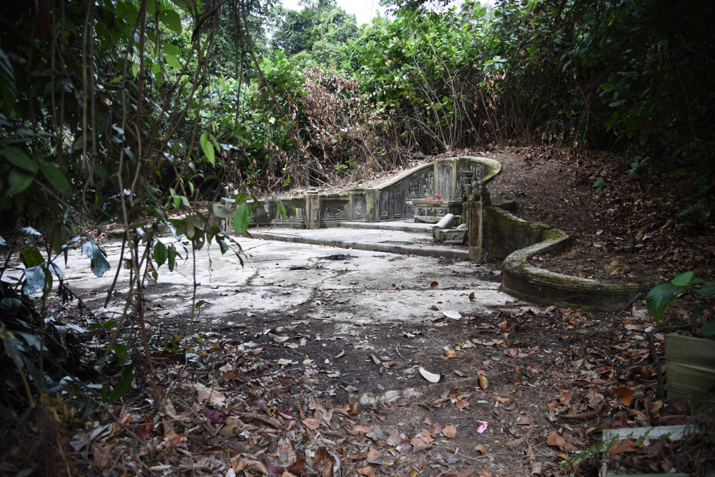 Wide shot of Teochew leader Seah Eu Chin's tomb at Grave Hill, surrounded by trees and vegetation, a historical landmark in Singapore. 