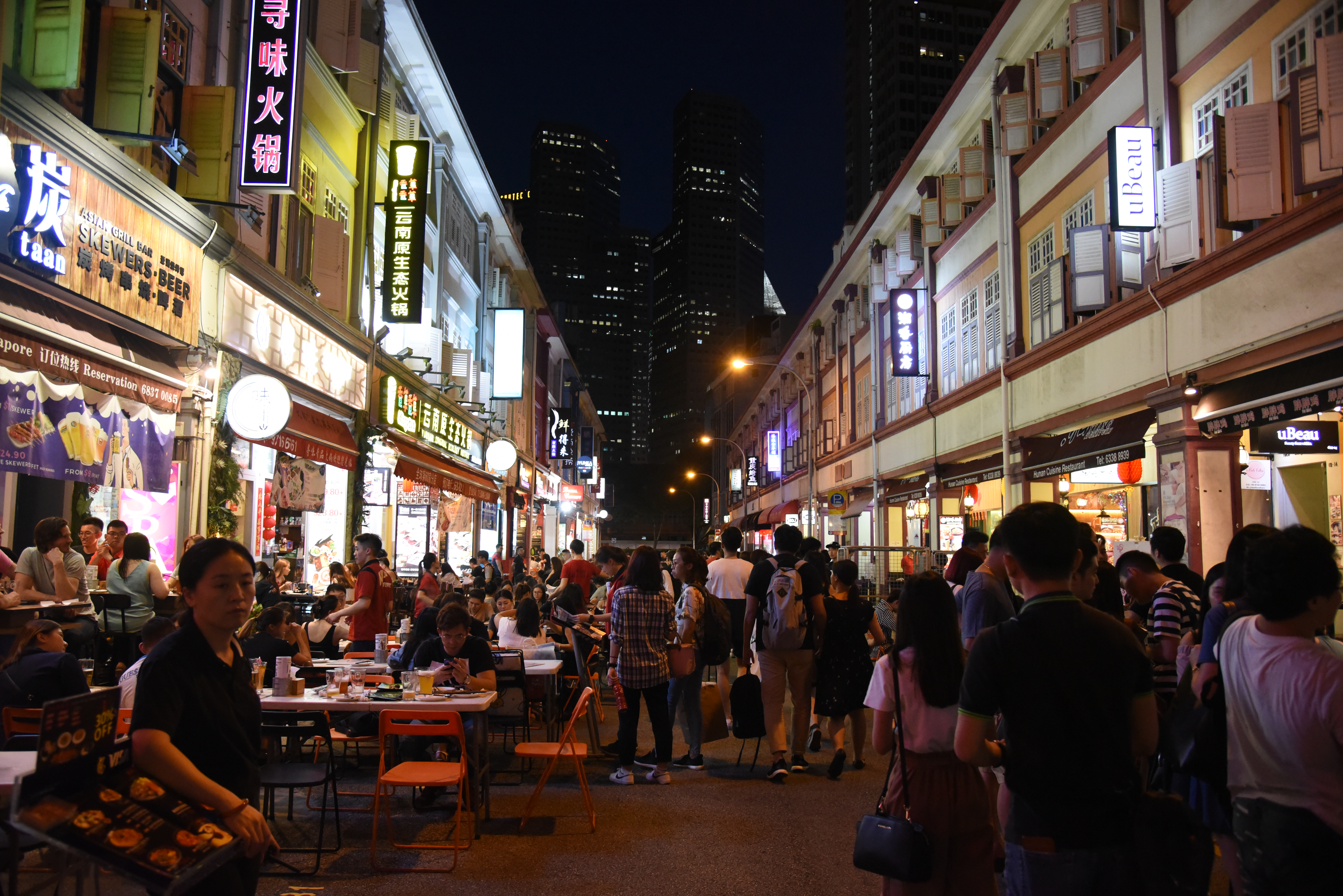 Street sign of Liang Seah Street at Bugis area, at night, with many people walking about the street. 