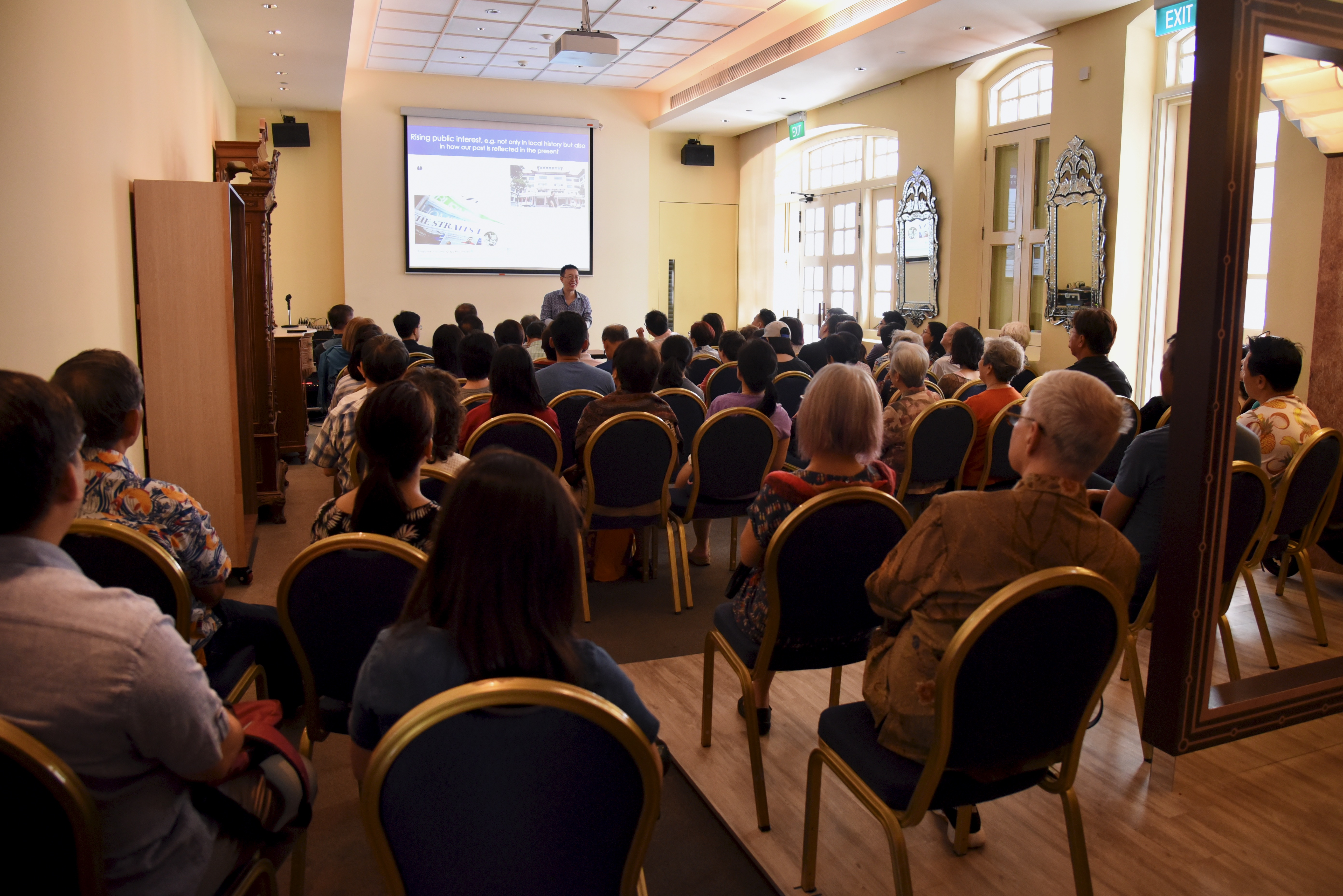 Wide shot of author and public speaker Shawn Seah at the Ixora Room at the Peranakan Museum, speaking to a large audience. 