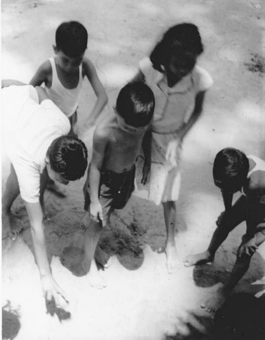 Young children playing marbles together outdoors in the kampung, in historical Aukang (Hougang). 
