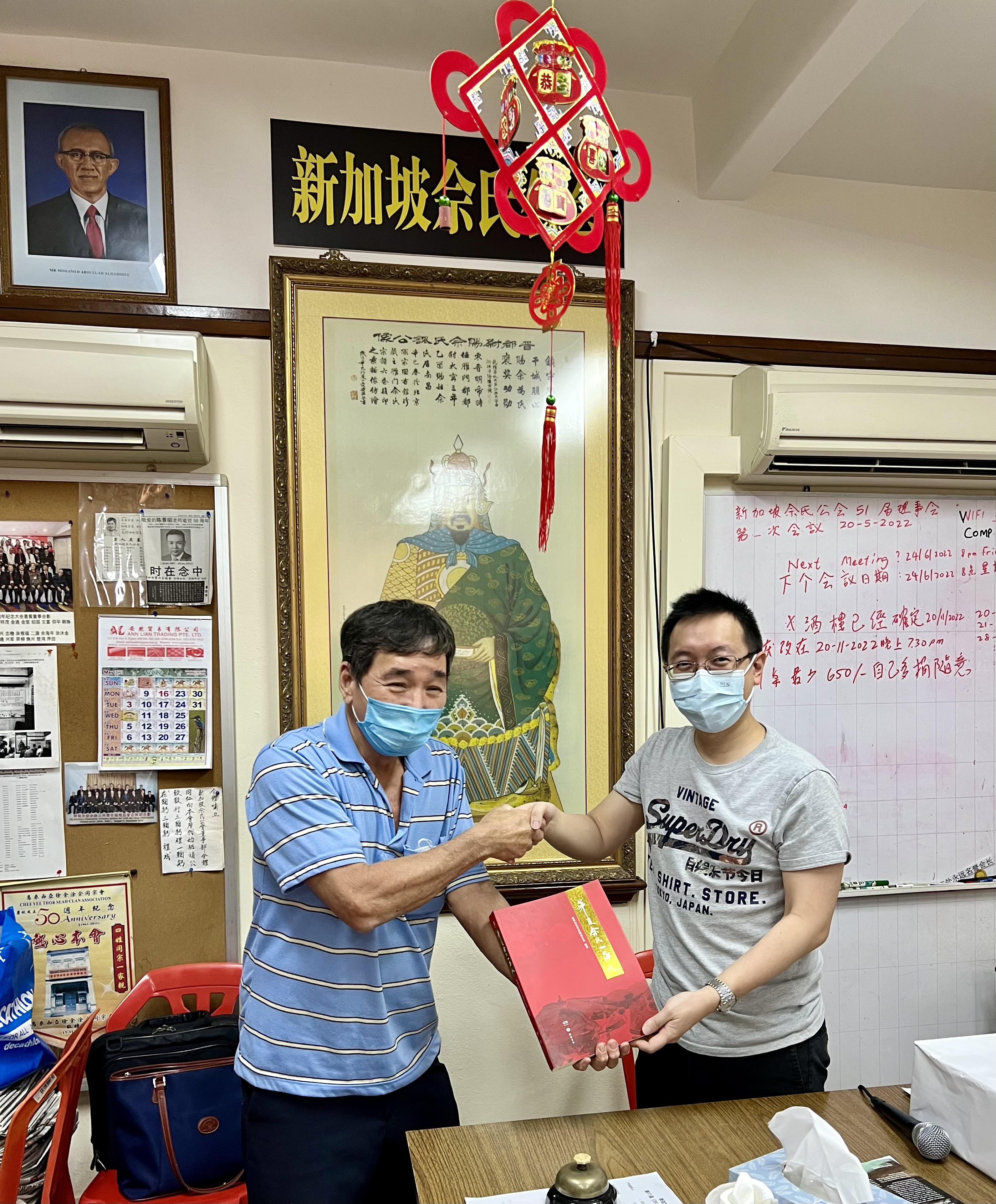 President David Siah of the Singapore Seah Clan Association awarding Shawn Seah a Chinese book and shaking hands. 