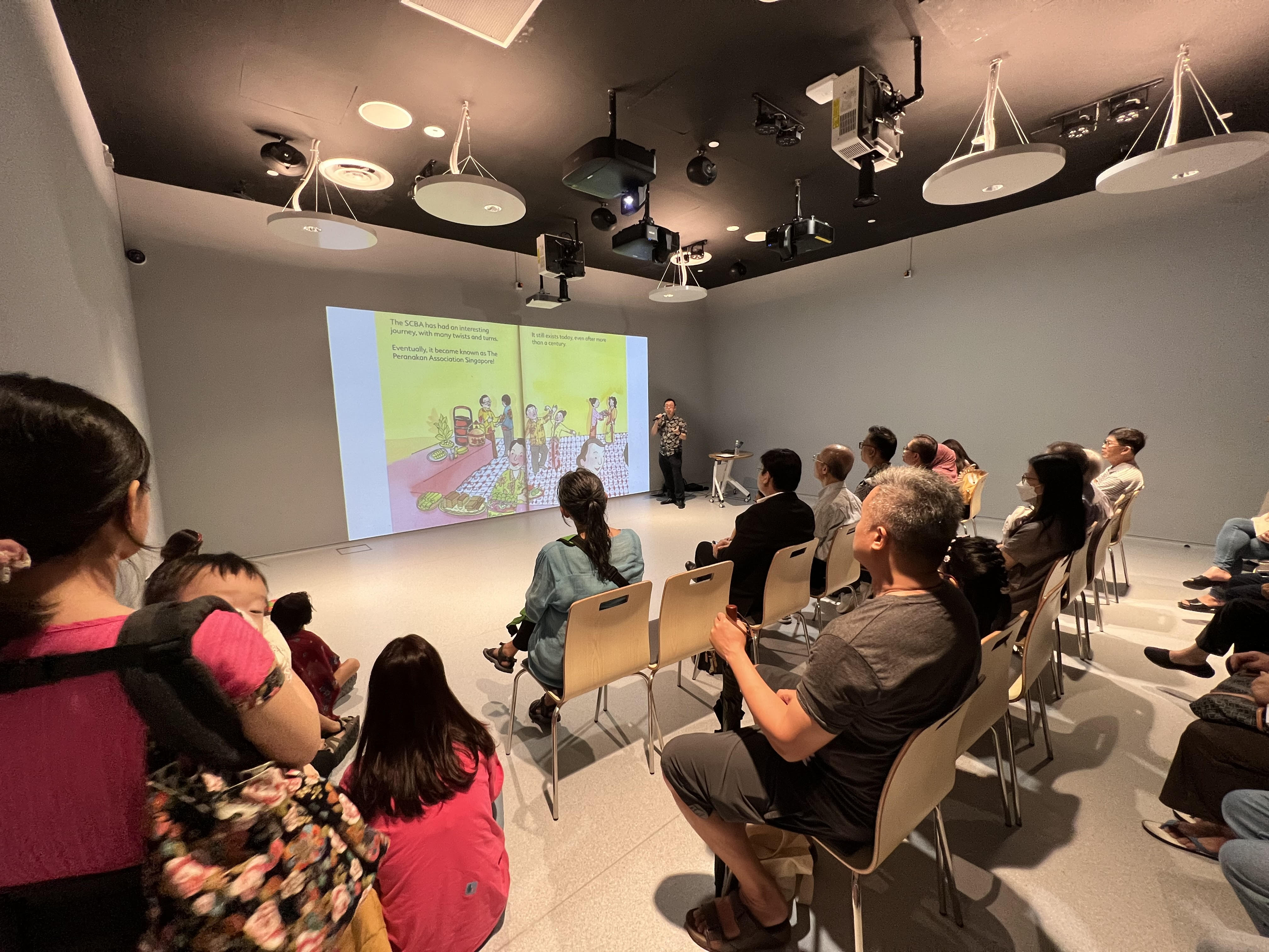 Children's book author Shawn Seah speaking in front of a crowd at the Stories Come Alive Room of the Punggol Regional Library. 