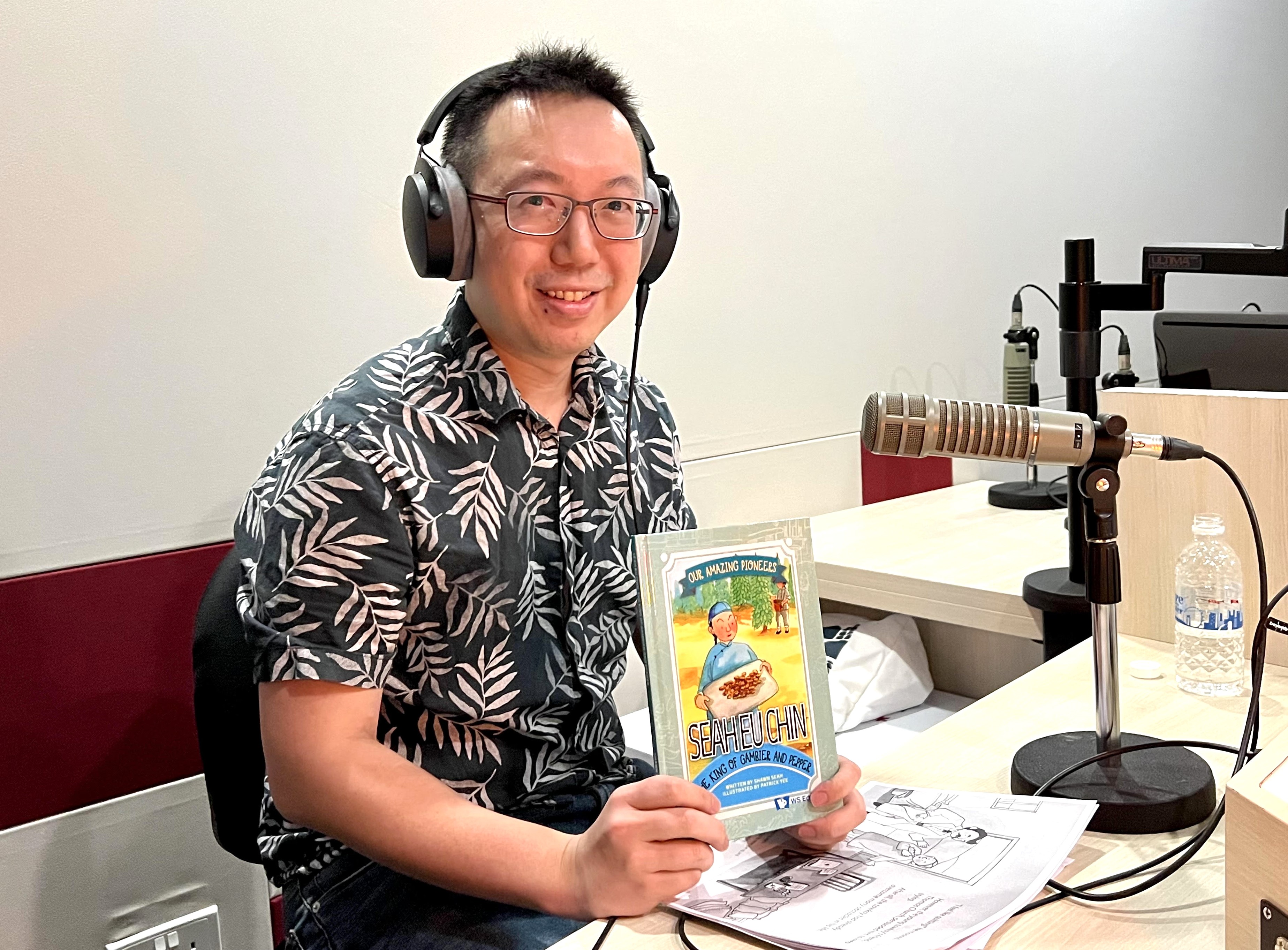 Author and speaker Shawn Seah holding a copy of his book at the radio station, behind the scenes.