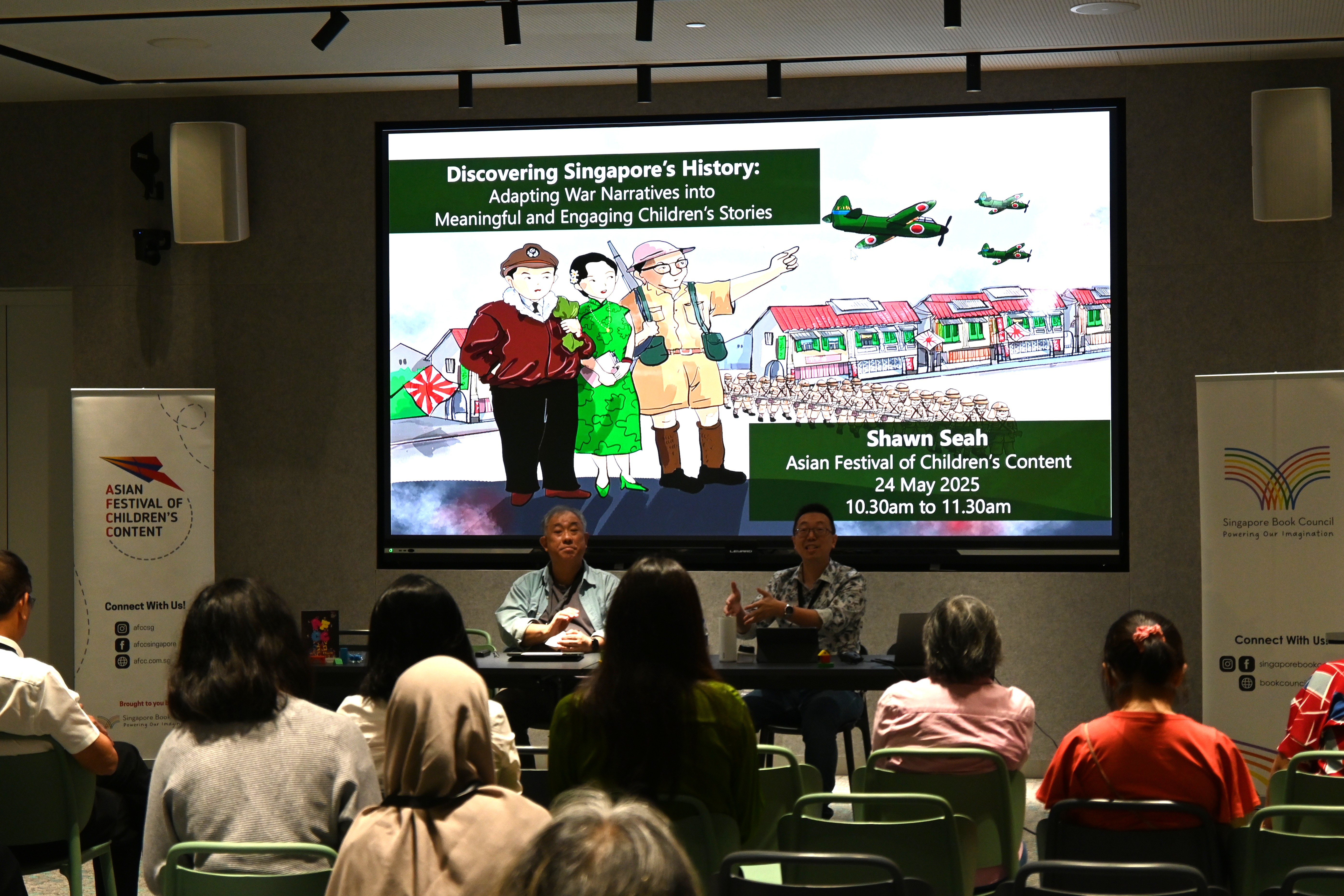 Author and speaker Shawn Seah speaking at the Asian Festival of Children's Content 2025, with David Liew moderating the session. 